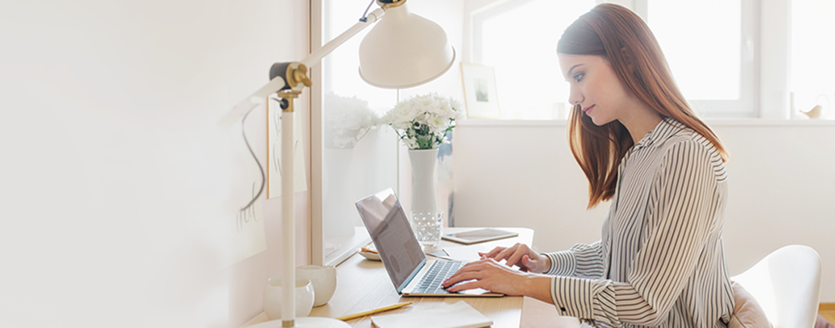 Młoda kobieta siedzące przy biurku i pracująca na laptopie