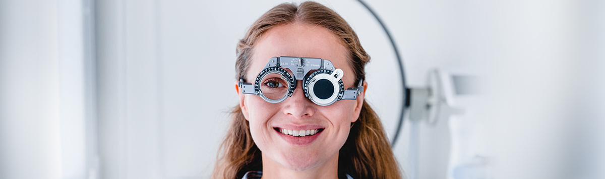 Wada refrakcji – uśmiechnięta kobieta w specjalnych okularach do badania wzroku