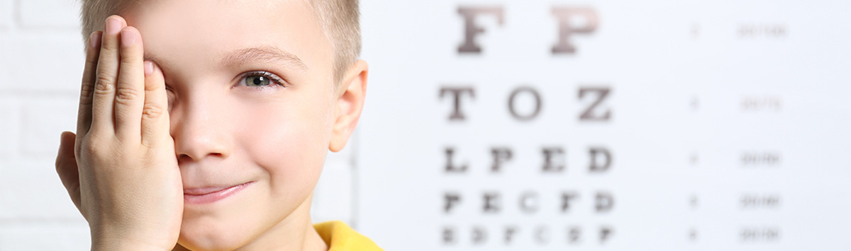 Badanie wzroku u dzieci – chłopiec zakrywający dłonią oko